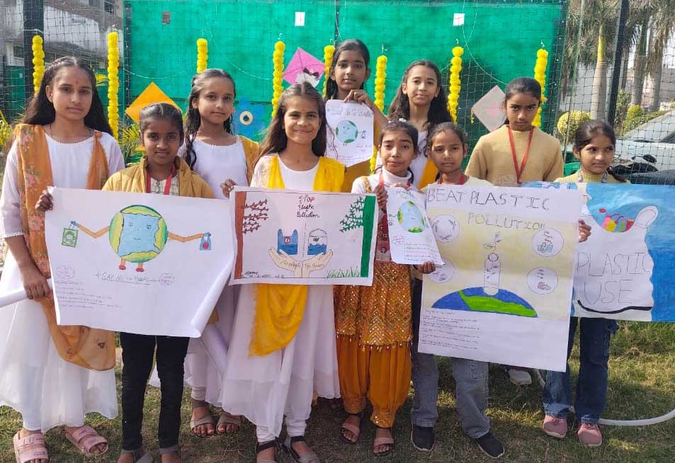 A group of smiling schoolgirls proudly display their "Beat Plastic Pollution" and "Stop Plastic Pollution" posters outdoors, promoting environmental awareness.